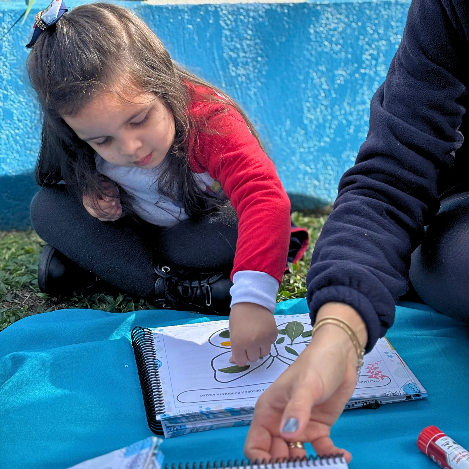 Aluna realizando uma atividade com folhas na área externa